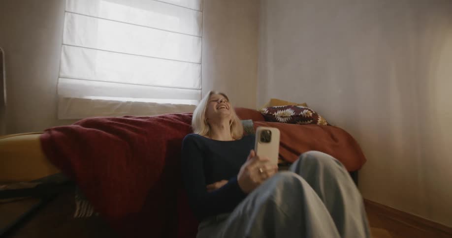 A woman laughs at something on a smart phone