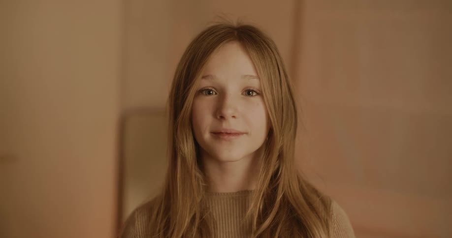 Girl with long hair standing against a plain background wearing a knitted sweater