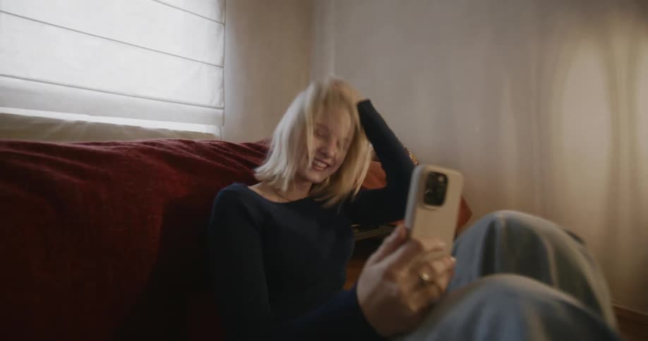 A girl laughs while looking at her cell phone