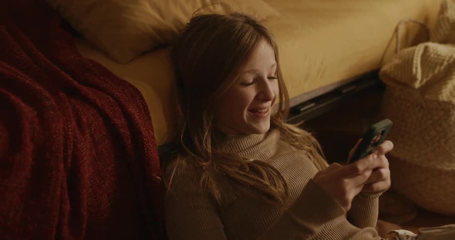 A girl smiles while using her cell phone