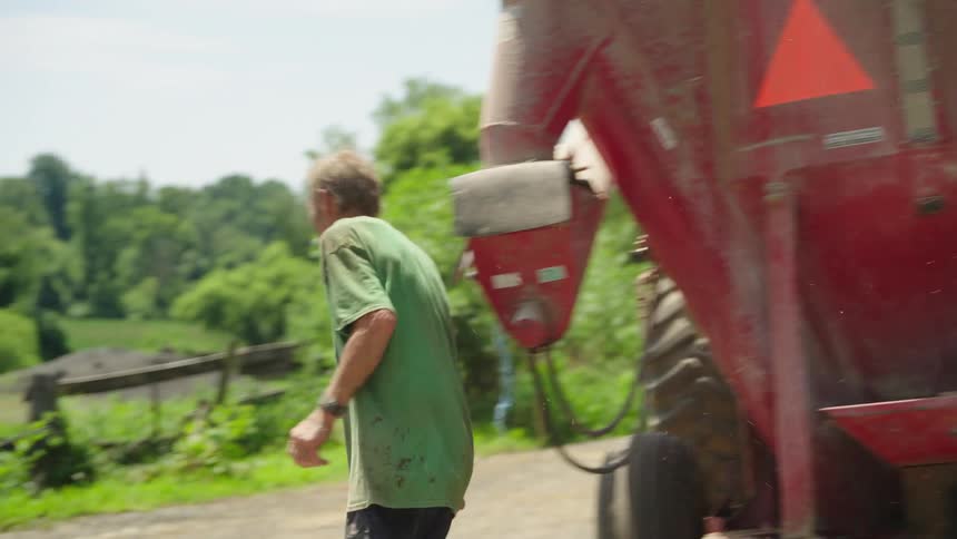 A man walking outdoor near farm machinery at midday