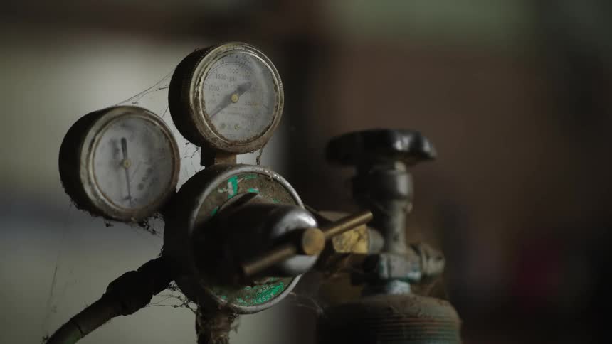Two old manometers covered in cobwebs connected to a gas bottle