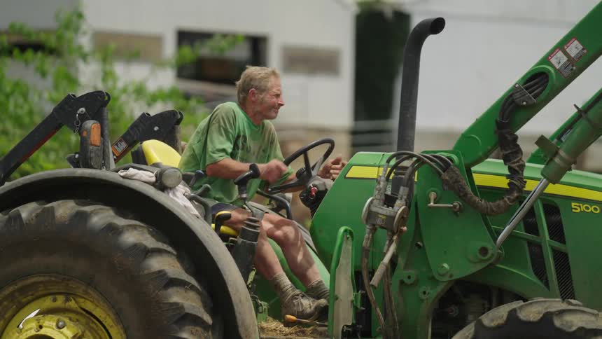 An old farmer driving a tractor in reverse