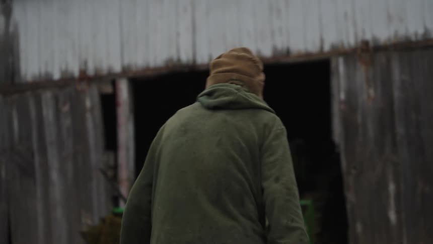 A person walking towards a tractor on the farm