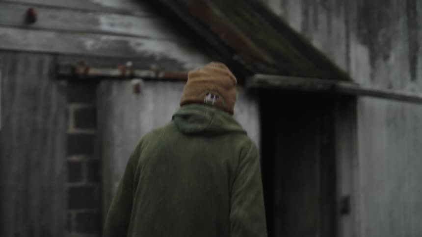 A person walking towards an old barn