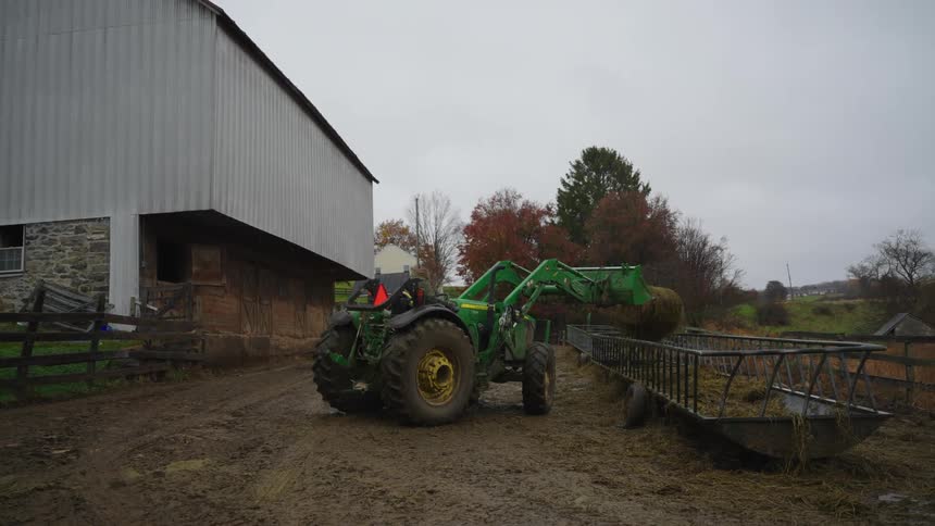 Man on a tractor removing dry grass from a site and placing it next to