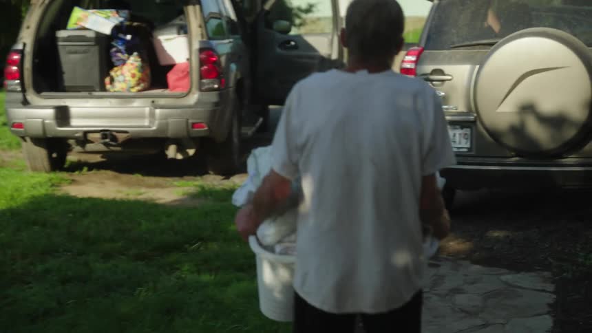 A man carrying a full laundry basket to his car