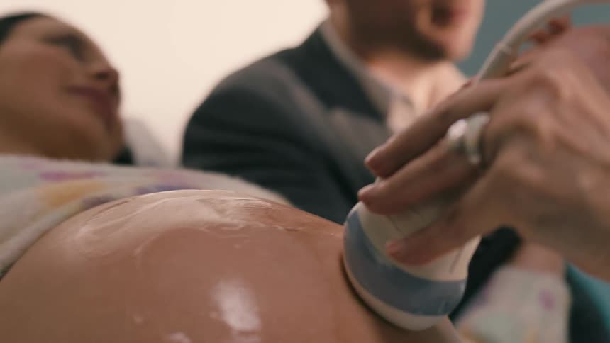 A man sitting beside his wife while her baby is been scanned from the belly