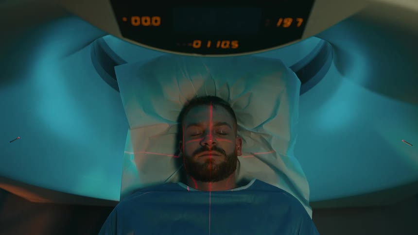 Patient with eyes closed coming out of an mri machine