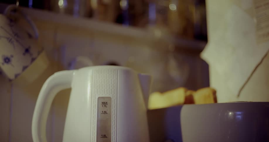 An electric kettle boils as two slices of toast pop up from a toaster