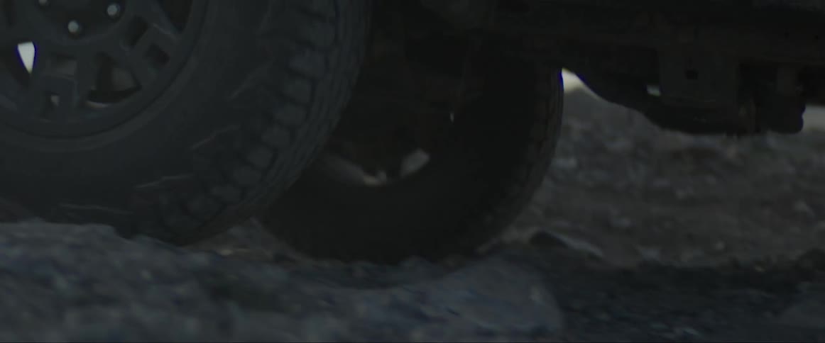 A vehicles wheel as it slowly drives off road on a rocky path