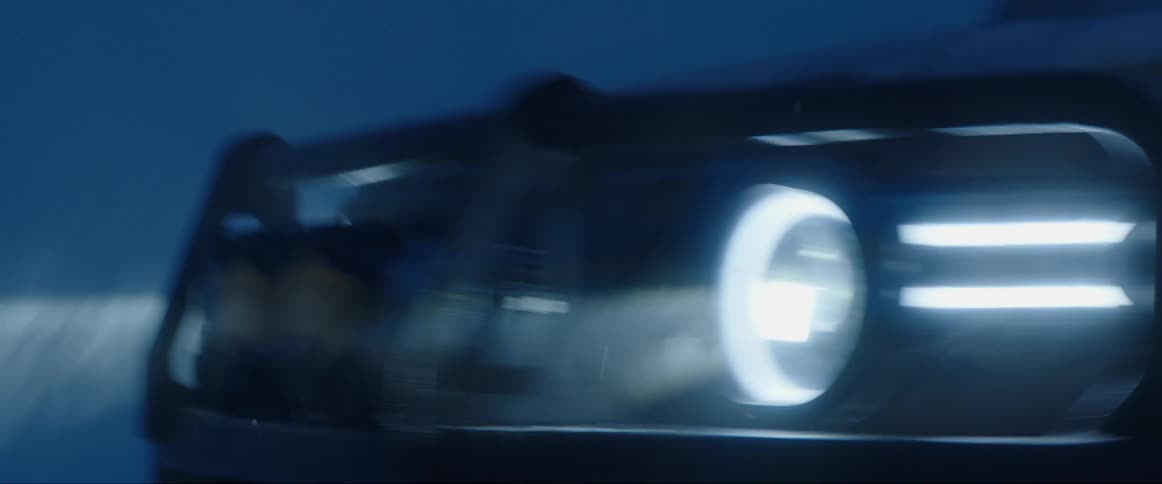 Vehicle drives through foggy night with bright headlights on