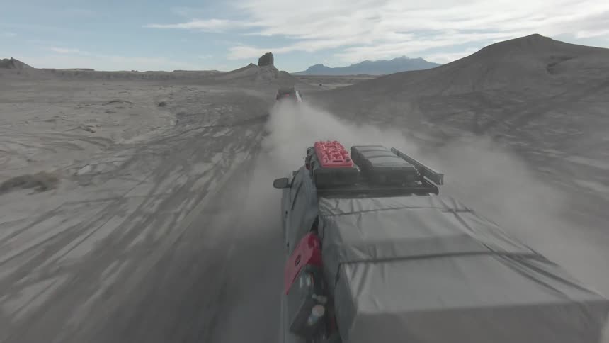 Two jeeps speeding along a desert road