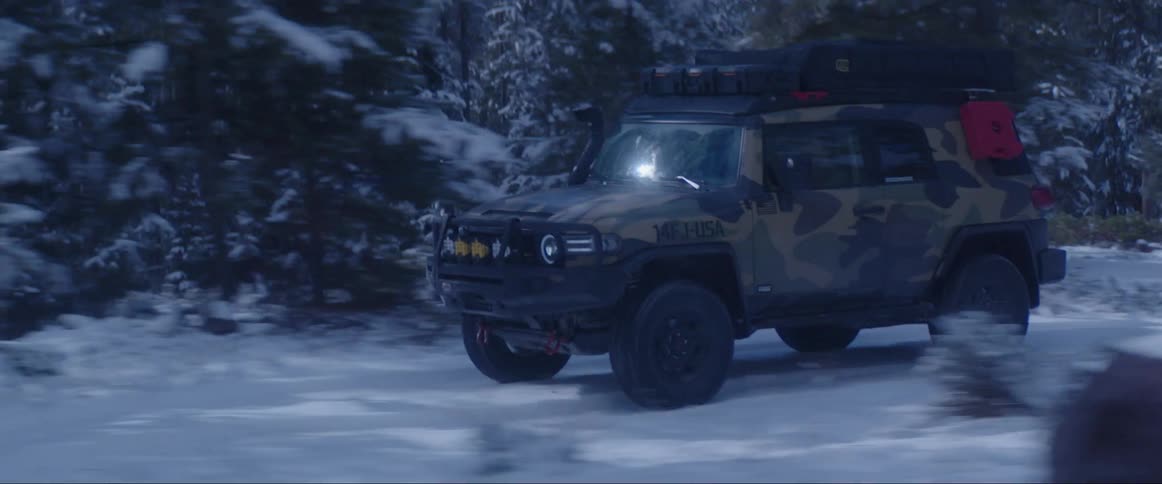 Adventure truck driving along a snowcovered road through the forest