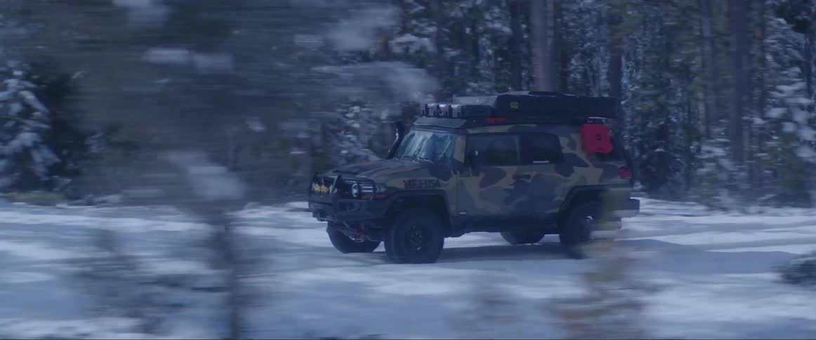Vehicles moving on a land covered in snows and trees on each sides at midday