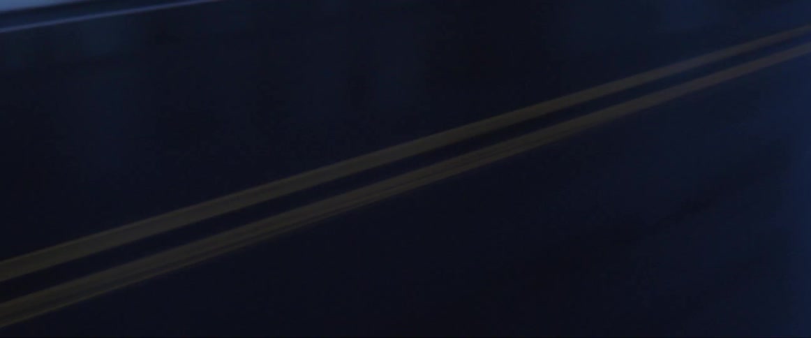 A wet road with yellow lines at night