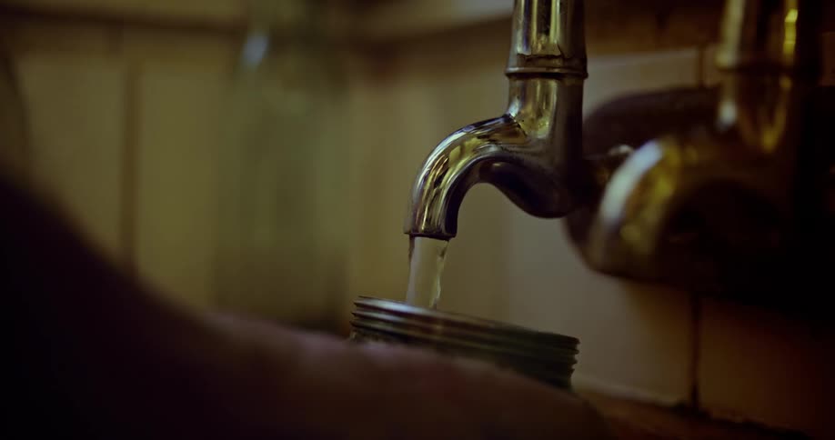 Person fills a coffee pot from an old fahioned sink faucet and then turns off the water