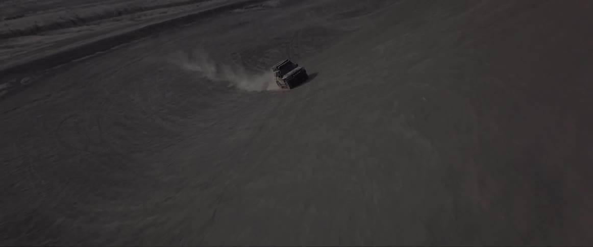 An off road vehicle driving fast over sand dunes in the desert