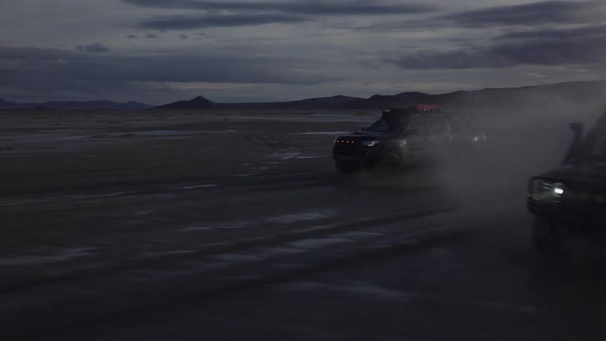 Two adventure trucks racing at high speed through a desert place
