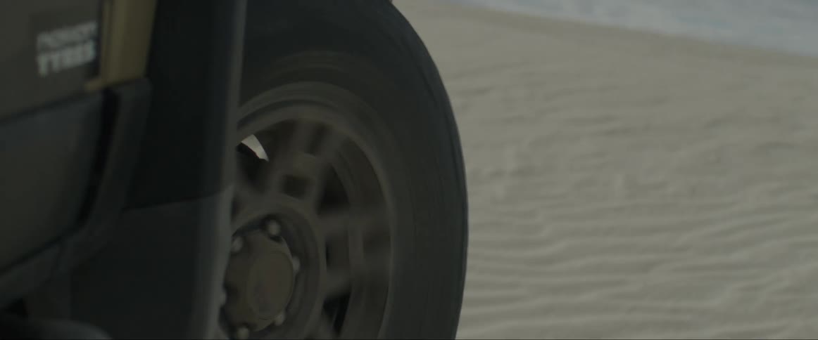 Closeup on the wheel of a pickup truck running through the sands and dunes