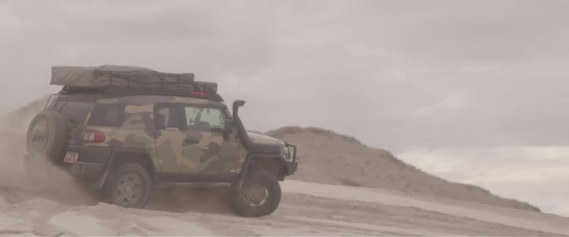 A car speeding in the desert during the day