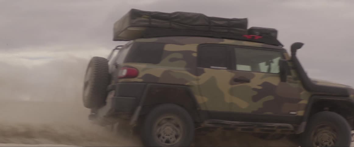 Adventure truck running through dunes on a cloudy day
