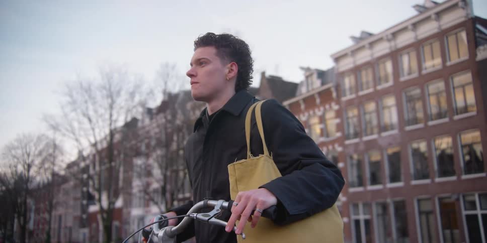 A teenager with a bag rides off on a bicycle