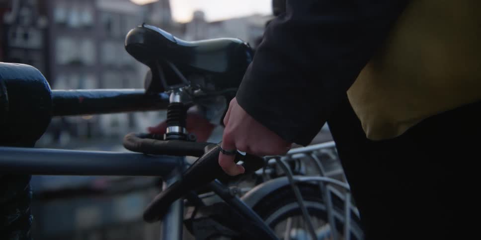 Man unlocks his bicycle from a handrail at sunset