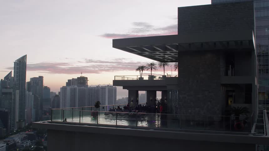A pool area on a rooftop with skyscrapers at sunset