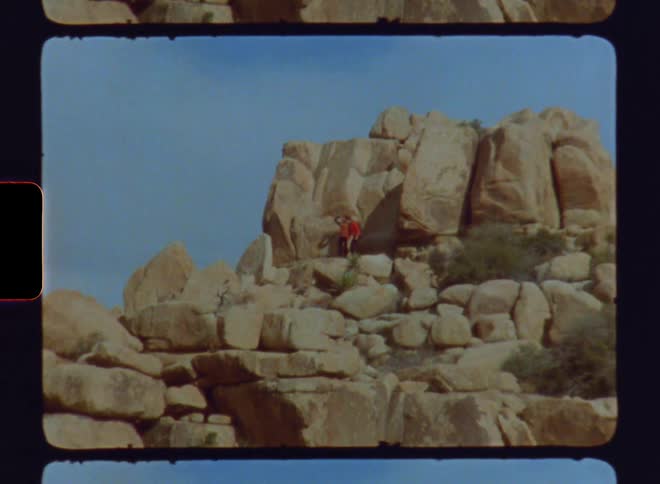 Two people in the middle of a canyon on a blue sky day