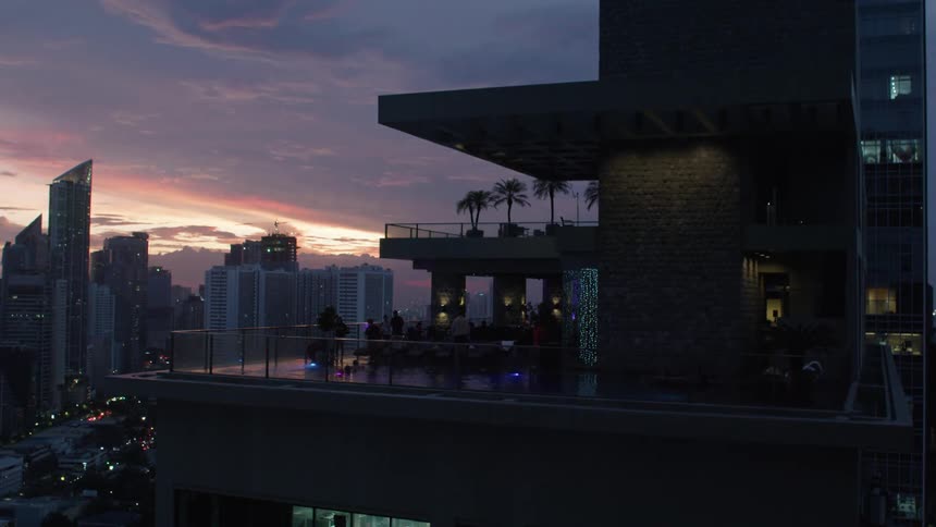 A night scene of a rooftop terrace and city skyline