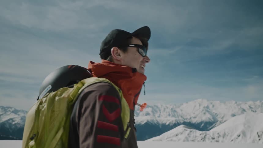 Man skitouring across snow covered plain bordering mountains