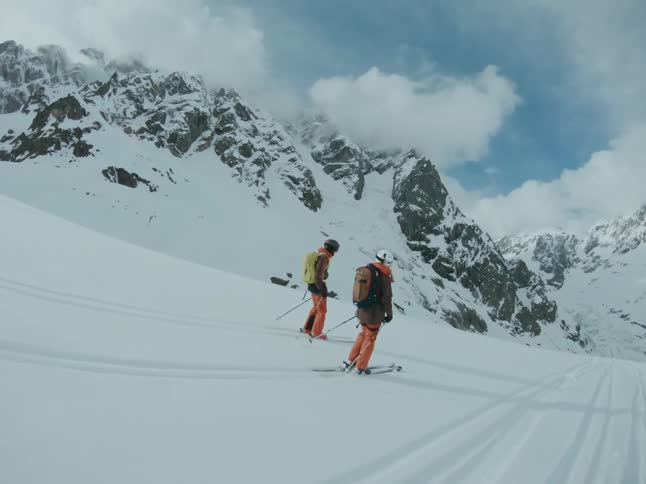 Two people ski in the middle of a snow-covered mountain
