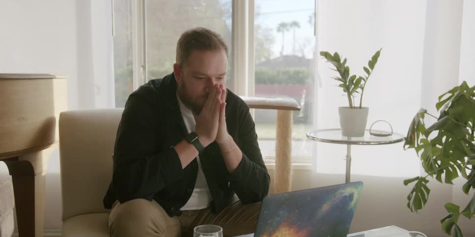 Young bearded man impatiently waiting in front of a laptop