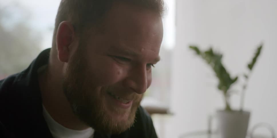 A man in a room laughing and talking
