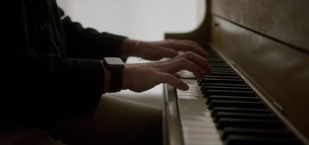 Hands of a person playing the piano in an indoor setting
