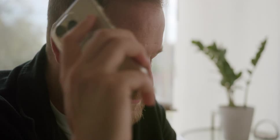 A man looking upset and frustrated while talking on a phone