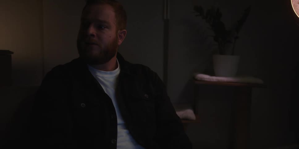 A man is sitting in a dark room