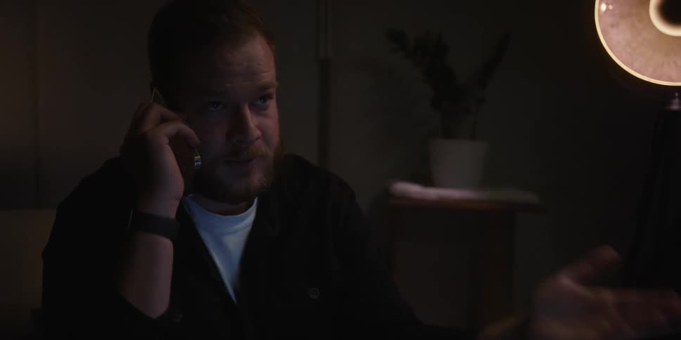 A man speaks into a phone while sitting in a living room