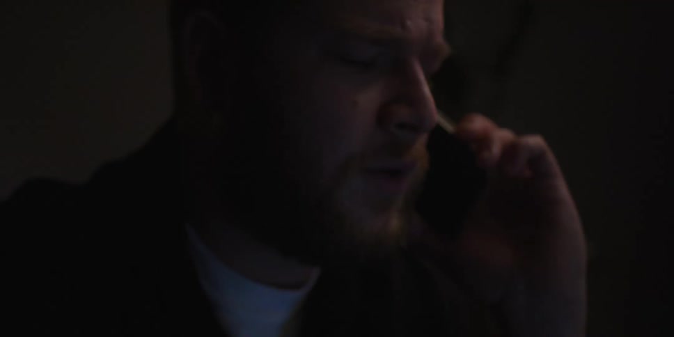 Man frowns during phone conversation at night