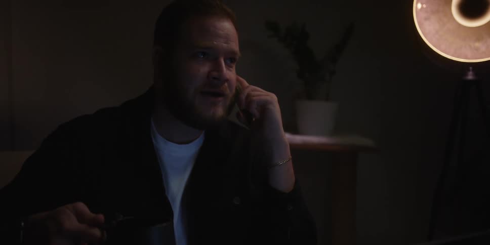 A man drinks tea while talking on his phone