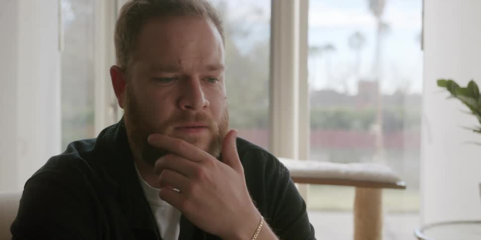 A man sighs and winces while speaking