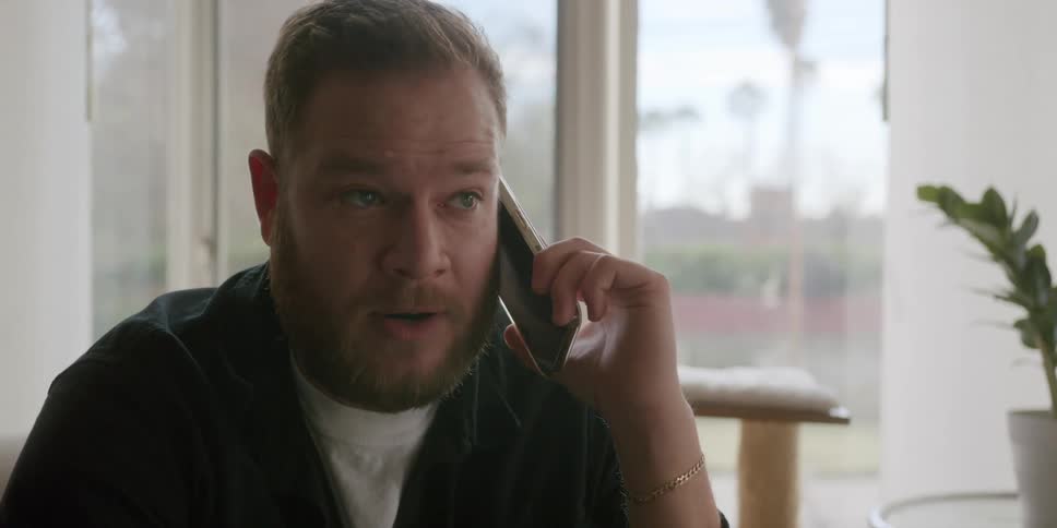 Sitting man gestures while talking on the phone