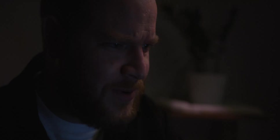 A man is talking and rubbing his beard