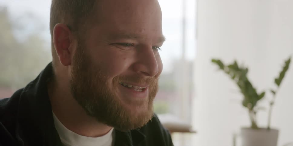 A young bearded man excitedly talking with someone