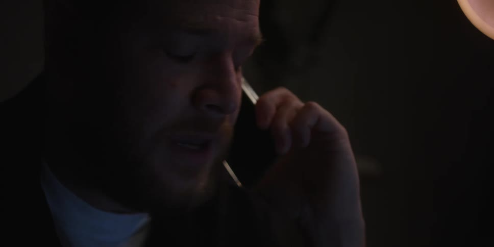 Upset man arguing on the phone in a dimly lit room