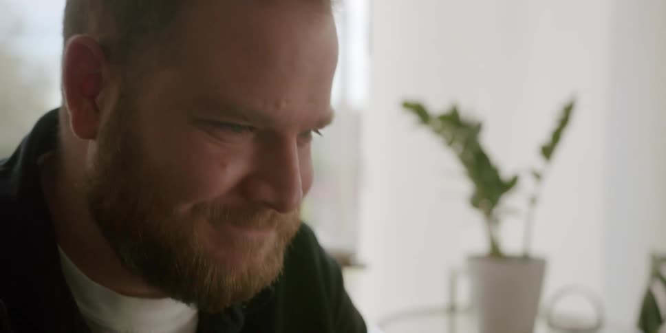 Bearded man smiles and waves during a video call