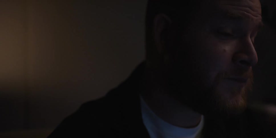 A man sitting in a dark room at night looking sad