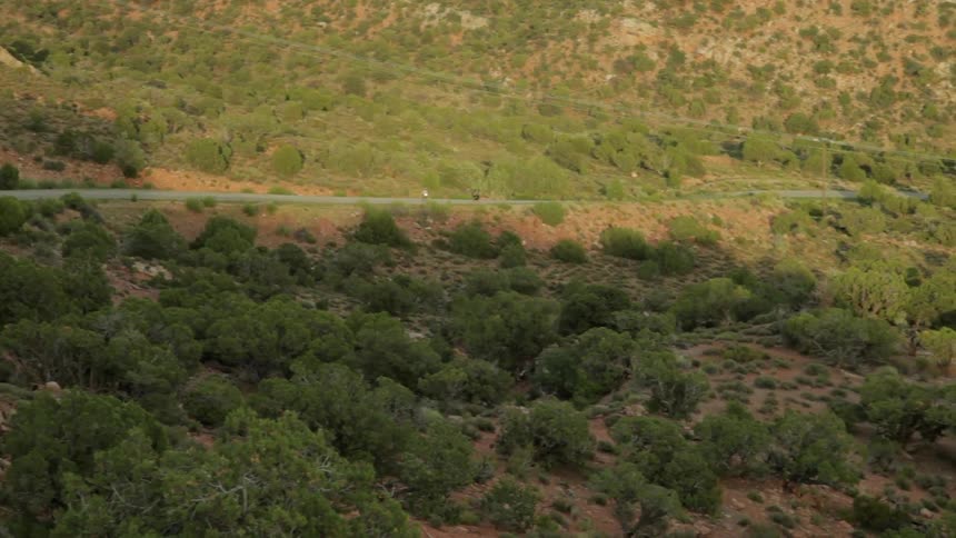 Two skateboarders ride down a mountain road