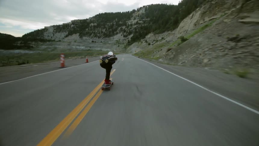 Man riding a skateboard down a mountain highway